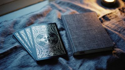 Колода таро на льняной ткани у окна, вечерний свет в комнате, рядом блокнот с одной фразой