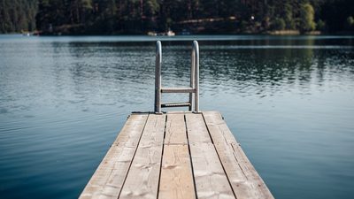 Молодая женщина в льняной рубашке стоит у открытого окна летним вечером в немецкой квартире