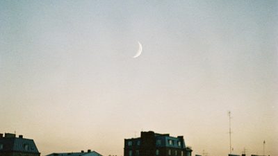 Раскрытый блокнот с написанными от руки намерениями и зажжённая свеча на столе в вечер новолуния