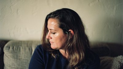 Профиль женщины в тихой комнате, она слушает в мягком вечернем свете настольной лампы