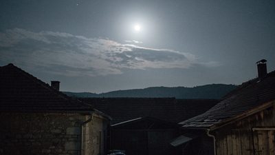 Полная луна высоко в ночном небе над тихим спящим двором