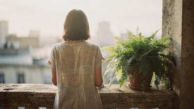 Женщина у окна с чашкой чая спокойно дышит в мягком утреннем свете
