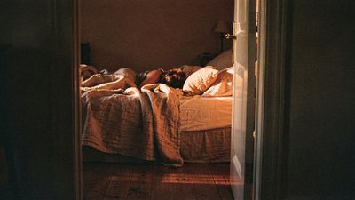 Женщина у окна с чашкой чая в мягком утреннем свете, спокойная домашняя сцена в тёплых тонах